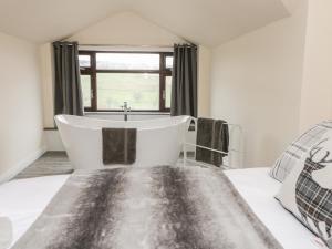 a bath tub in a bedroom with a window at Little Barn in Keighley