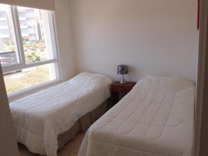 Duas camas num quarto com uma janela em Acogedor Departamento en Balneario de Papudo-Condominio Lomas de Papudo 1 -Punta de Puyai em Papudo