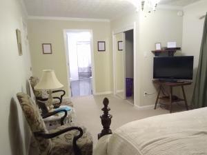 um quarto com uma cama, uma cadeira e uma televisão em Serenity Hill Bed and Breakfast em Sloans Crossing