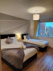 two beds in a hotel room with a window at Wild Atlantic Apartments Killarney in Killarney