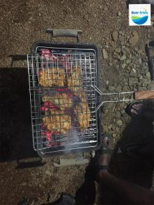 a person is cooking food on a grill at River Arena Holidays in Vagamon