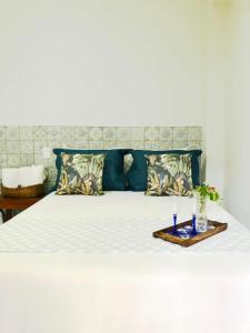 Una cama blanca con dos vasos en una bandeja en lux pousada, en Porto Seguro