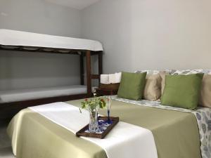 Una habitación con dos camas y un jarrón de flores sobre una mesa. en lux pousada, en Porto Seguro