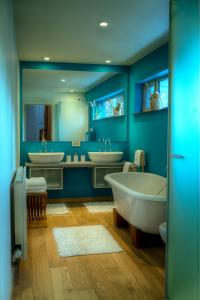 a blue bathroom with two sinks and two tubs at Menin Gate House in Ypres