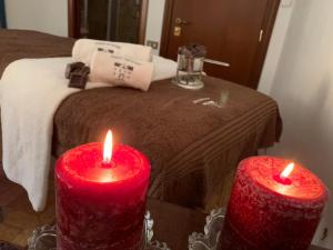 two red candles on a table in front of a bed at Domus Socolatae Residenza d'Epoca Charming B&B - Adults Only in Follonica