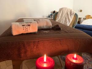 due candele rosse sono su un tavolo con asciugamani di Domus Socolatae Residenza d'Epoca Charming B&B - Adults Only a Follonica