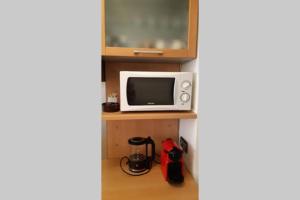 a room with a microwave and a tv on a shelf at Appartement cosy dans le centre historique in Saint-Germain-en-Laye