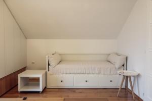 a white bed in a white room with a stool at Rural House Veranda in Šarengrad