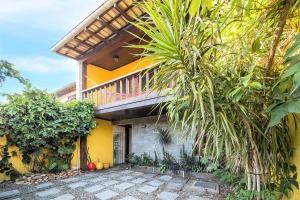 uma casa amarela com uma varanda em cima em Búzios Samba Suítes em Búzios