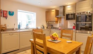 a kitchen with a wooden table with a bowl of fruit on it at The Cottage in Benllech