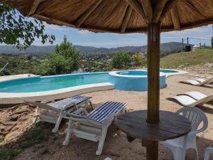 a patio with a table and chairs and a pool at Cabañas Los Álamos in Villa Carlos Paz