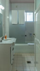a white bathroom with a shower and a sink at Habitación en La Casa de Mis Padres in Mendoza