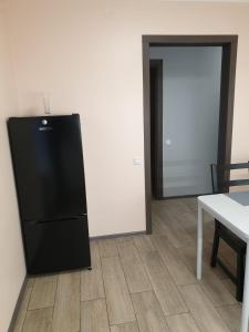una nevera negra en una habitación con mesa y puerta en Swan City Apartment, en Gulbene