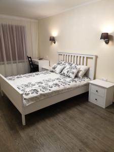 a bedroom with a white bed and a table and a desk at Swan City Apartment in Gulbene