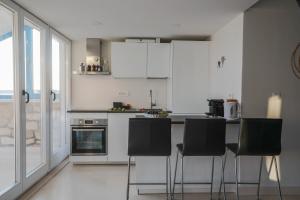 una cocina con armarios blancos y sillas negras en Penthouse in old Dalmatian house - Flybridge en Hvar
