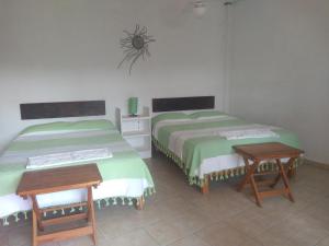 twee bedden in een kamer met twee tafels bij La Casa del Volcan in Tlayacapan