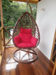 a red couch in a hanging chair on a porch at Ibiza Tropical Beach Villas in Uvita