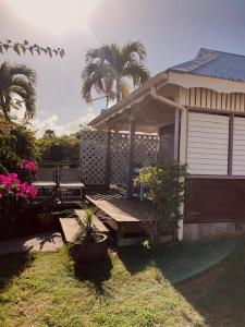 einen Hinterhof mit einer Holzbank und einem Haus in der Unterkunft cocon caraibe in Sainte-Anne