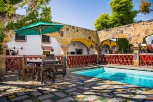 a table with an umbrella next to a swimming pool at Hotel Cosmos Don Carlos in Mexicali