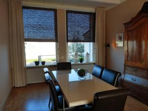 a dining room with a table and chairs and two windows at APARTMENT BY THE SEA Bed by the Sea in Vlissingen