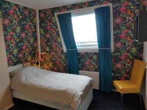 フリシンゲンにあるAPARTMENT BY THE SEA Bed by the Seaのベッドルーム1室(ベッド1台付)、花の壁紙の窓が備わります。