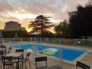 a swimming pool with tables and chairs next to at Novotel Caen Côte de Nacre in Caen