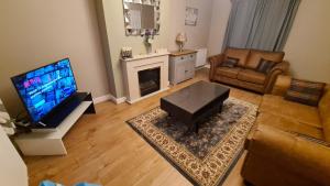 a living room with a television and a couch and a table at Spacious 3 Bedroom House, 6 beds in Spondon, Derby with Parking in Derby