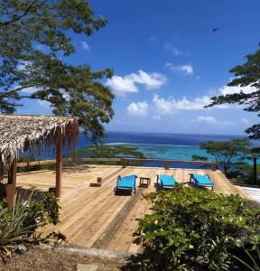 un complejo con sillas azules y el océano en L'Auberge Polynésienne en Tevaitoa