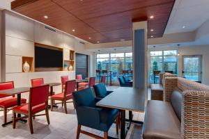 a restaurant with tables and chairs and a flat screen tv at Holiday Inn Express & Suites - Middletown - Goshen by IHG in Middletown