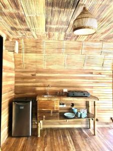 a kitchen with a wooden wall with a table and a sink at Buena Onda Bungalows in Santa Teresa Beach