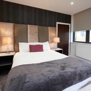 um quarto com uma grande cama branca e 2 candeeiros em LuxuStay Serviced Apartments em Milton Keynes