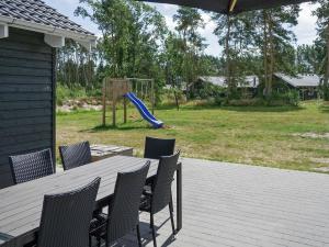 patio con mesa, sillas y parque infantil en 22 person holiday home in Nex, en Bedegård