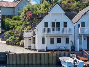 a white house with a boat in the water at 6 person holiday home in Urangsvåg in Steinsbø