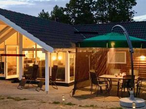 eine Terrasse mit einem Tisch und einem grünen Sonnenschirm in der Unterkunft Two-Bedroom Holiday home in Hornbæk 2 in Rødby