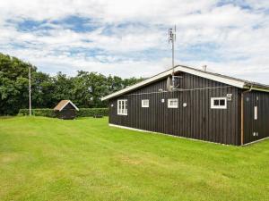 a black building in a field with a grass yard at 8 person holiday home in Hemmet in Hemmet