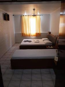 um pequeno quarto com 2 camas e uma janela em Hotel Mustang em São Paulo