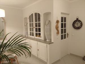 フェラグドにあるThree Palms Apartmentの白いキャビネットと壁掛け時計付きのキッチン