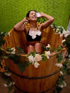 una mujer sentada en una bañera de madera llena de flores en Fun Retreat Resort, Hotel and Ayurveda Spa en Arusha
