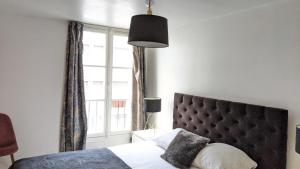 a bedroom with a bed and a large window at Opera Louvre Holiday Apartment in Paris