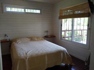 a bedroom with a bed and two windows at Los Sauces in Tigre