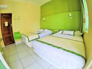 a hotel room with two beds and a green wall at Casa Mia in Puerto Escondido