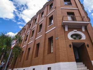 a tall brick building with a window and a balcony at Hotel Santa Cruz in Santa Cruz do Sul