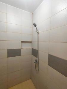 a shower in a bathroom with white and gray tiles at Innskeep in Calingcuan