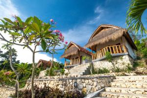 a house with a thatched roof and stairs at NG Sweet Home in Nusa Penida