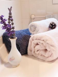 a white vase with purple flowers in it next to towels at Rosewood Park Guest Suite in Yarragon