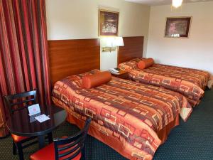 Cette chambre d'hôtel comprend deux lits, une table et des chaises. dans l'établissement Country Hearth Inn-Union City, à Union City