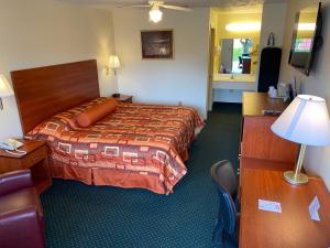 Habitación de hotel con cama y escritorio con lámpara. en Country Hearth Inn-Union City en Union City