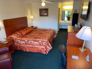 a hotel room with a bed and a desk with a lamp at Country Hearth Inn-Union City in Union City +9 photos