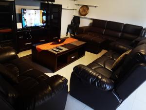 a living room with leather furniture and a flat screen tv at Tuvawa Luxury Suites in Walvis Bay