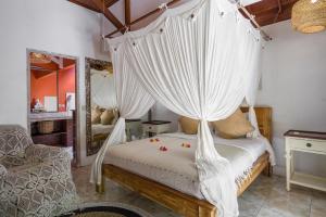 a bedroom with a canopy bed with white drapes at Ocean Star Villa Five near the KuDeTa Beach in Seminyak